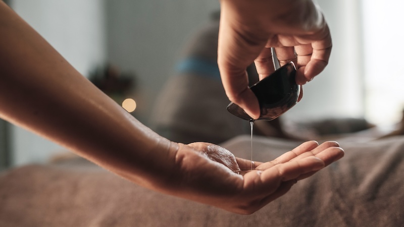 Massage therapist pouring massage oil into hands